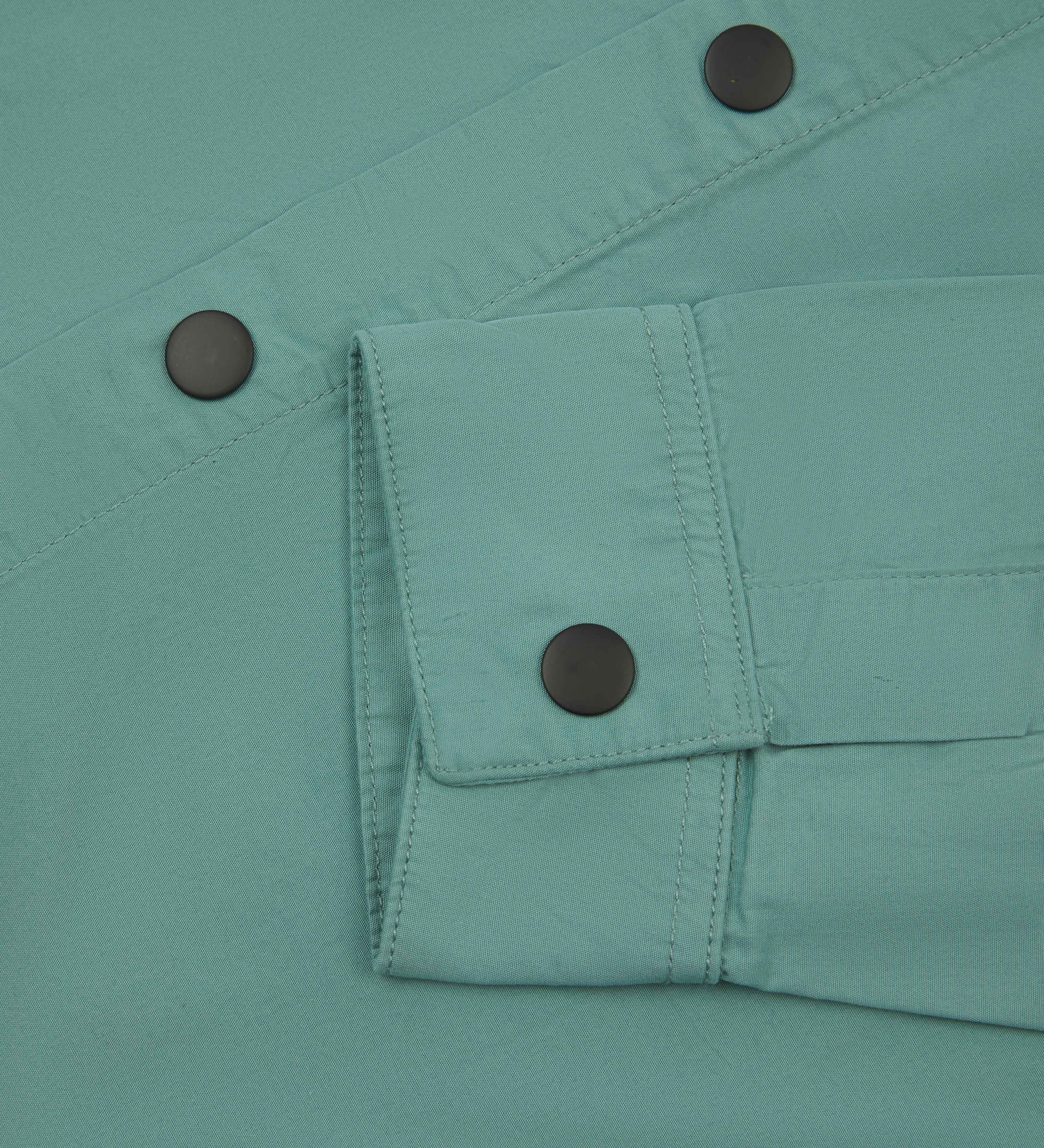 front flat shot of eucalyptus green uskees men's lightweight shirt with popper front and cuff fastening in close-up