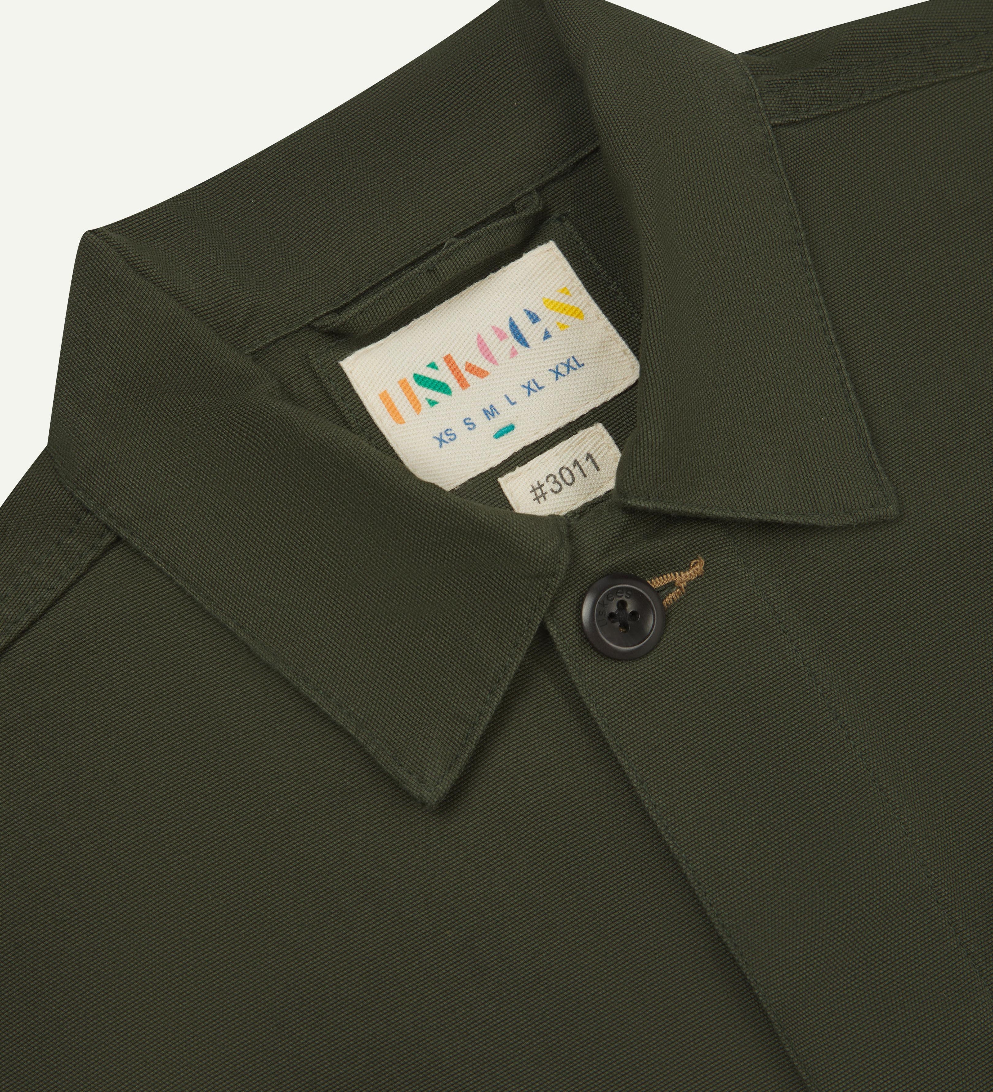 Front close up view of uskees men's dark green overshirt with hidden buttons showing the neck label