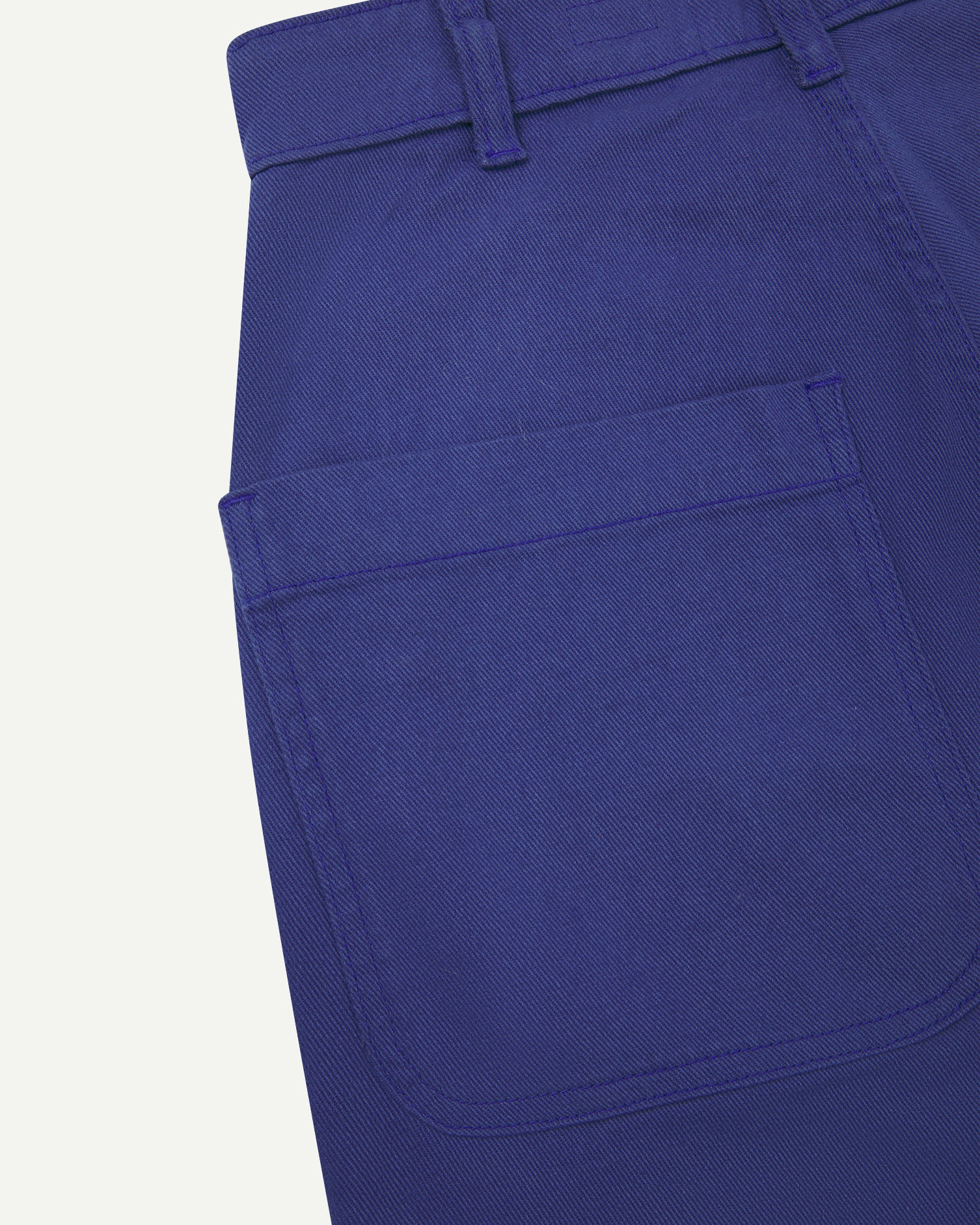 Back close-up view of Uskees cotton drill 'commuter' trousers for men in ultra blue showing belt loops and back pocket.