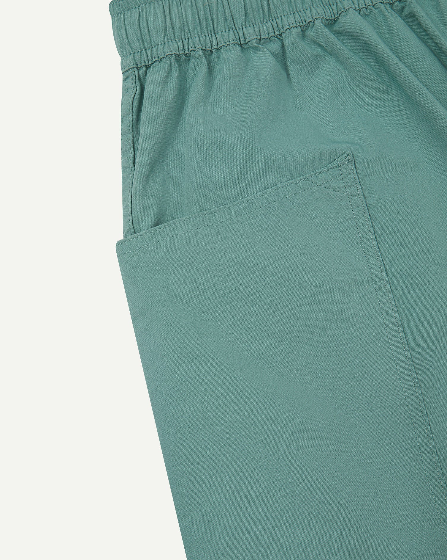 Close-up view of eucalyptus green organic cotton #5015 lightweight cotton shorts by Uskees showing elasticated waist and deep front pocket.