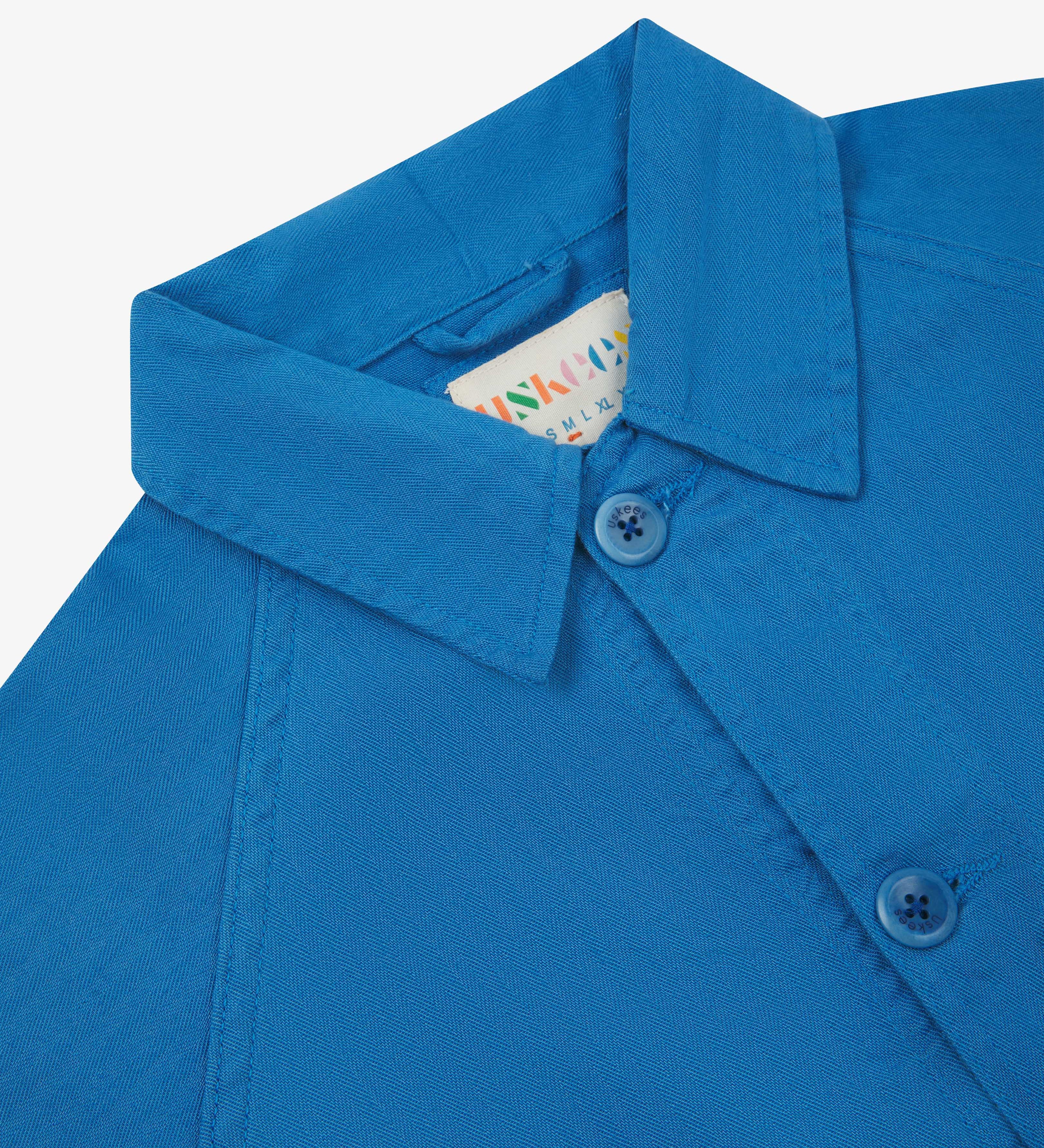 Neck view of Uskees 3041 opal-blue herringbone cotton signal jacket with focus on collar, Uskees brand label and matching corozo buttons.