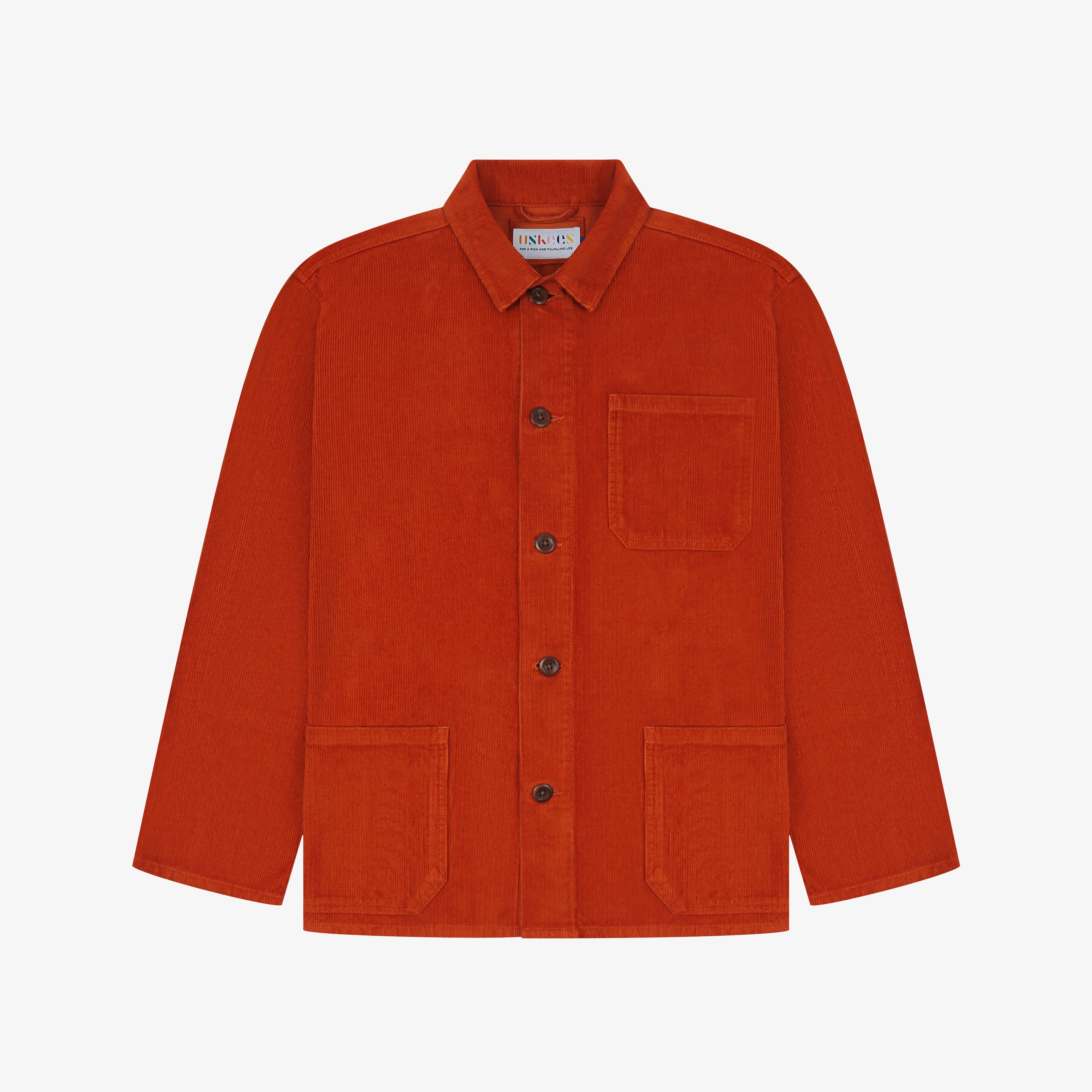 Front flat shot of rust-red, buttoned corduroy overshirt. Clear view of chest and hip pockets, corozo buttons and Uskees branding label.