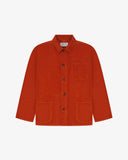 Front flat shot of rust-red, buttoned corduroy overshirt. Clear view of chest and hip pockets, corozo buttons and Uskees branding label.