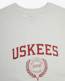 Close up shot of a men's white graphic t-shirt with 'USKEES' logo in red on the front. Presented on a white background