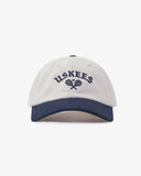 Cream baseball cap with navy peak and 'USKEES' logo on front, presented on a white background