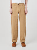 Bottom half of male model wearing beige Uskees painter pants and brown shoes, presented on a white background