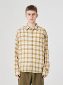 Male model wearing an Uskees long sleeved  plaid shirt and green trousers, presented on a plain background