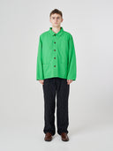 Male model wearing a bright green Uskees shirt jacket buttoned up and dark blue pants on a white background