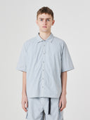 Front view of a male model wearing an Uskees light blue short-sleeve button front shirt, presented on a white background