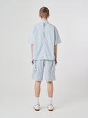 Back view of a male model wearing an Uskees light blue short-sleeve shirt and shorts outfit, presented on a white background.