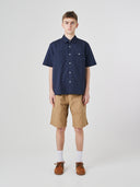 Front shot of a male model wearing a dark blue short sleeve Uskees shirt and beige shorts on a white background