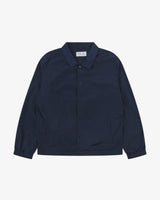 Front flat shot of Uskees dark blue polyester coach's jacket sgowing front poppers on a grey background.