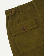 Close-up of green corduroy pants with a buttoned back pocket and waist adjuster buttons on a white background