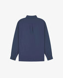 Flat back view of mid blue organic chambray Oxford shirt from Uskees with view of open pleat and longer rear hem so it can be tucked in more easily.