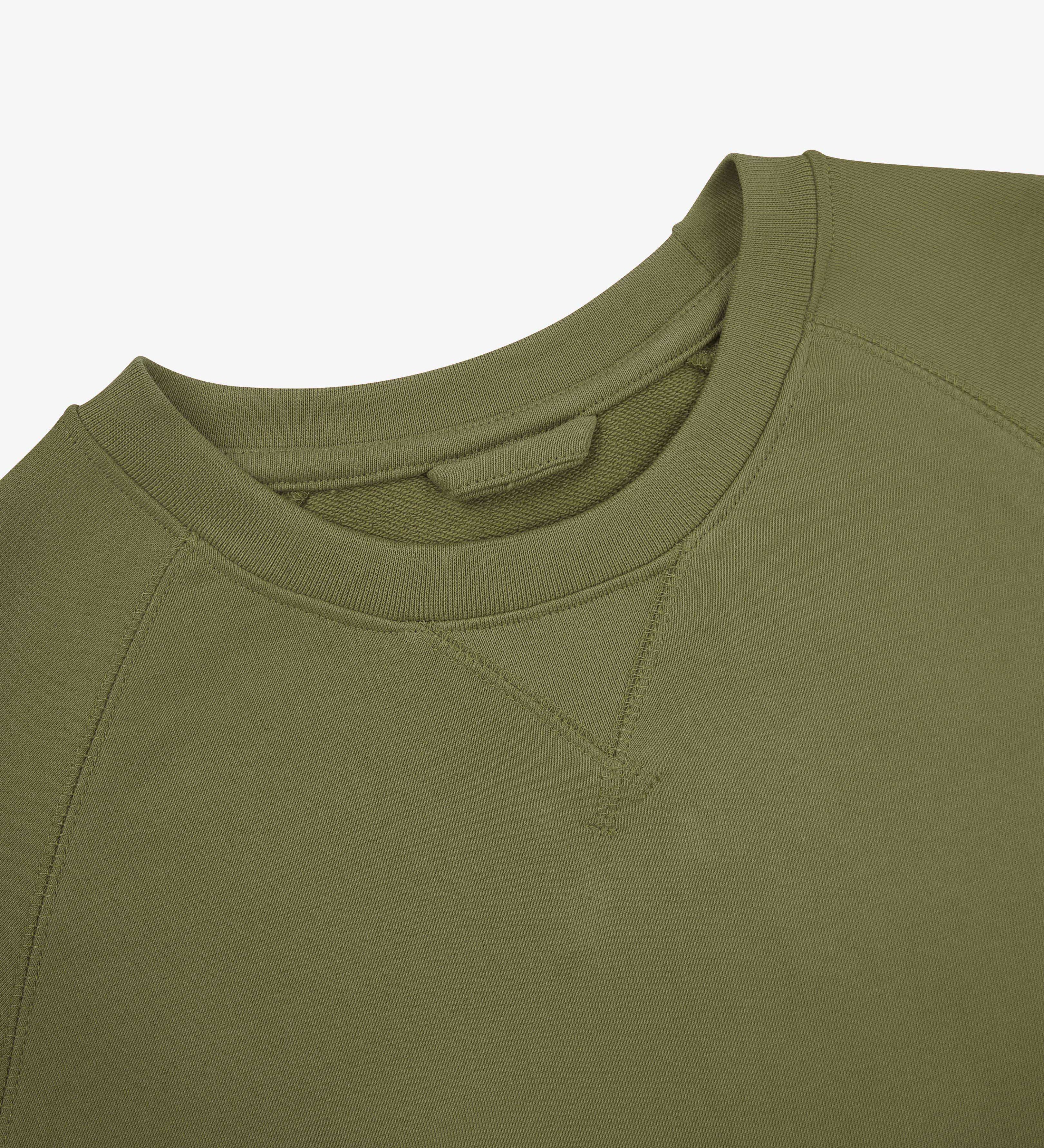 Close-up of an Uskees herb green sweatshirt on a light gray background