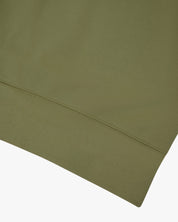 Close-up of an Uskees herb green sweatshirt showing the hem detail