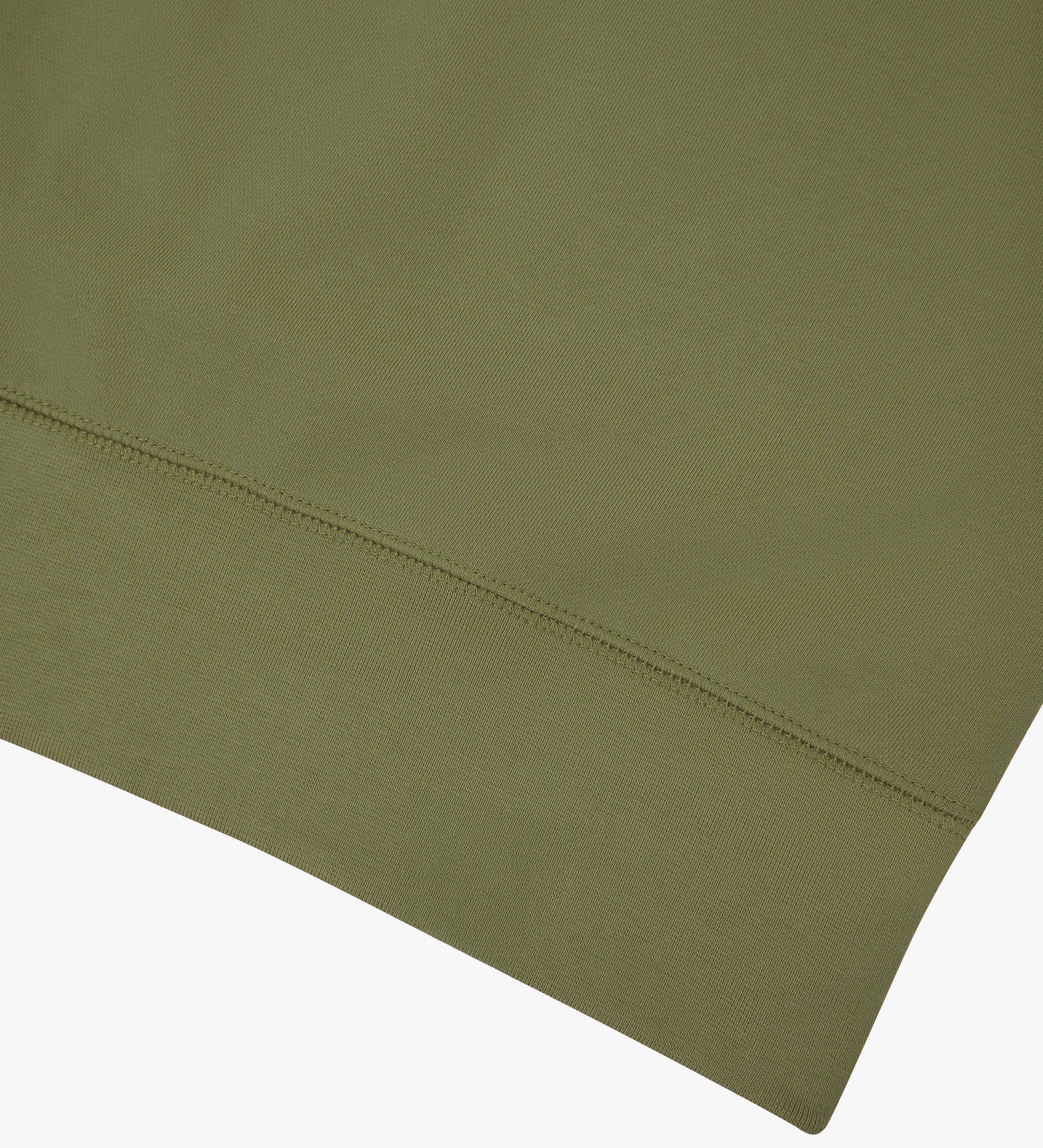 Close-up of an Uskees herb green sweatshirt showing the hem detail