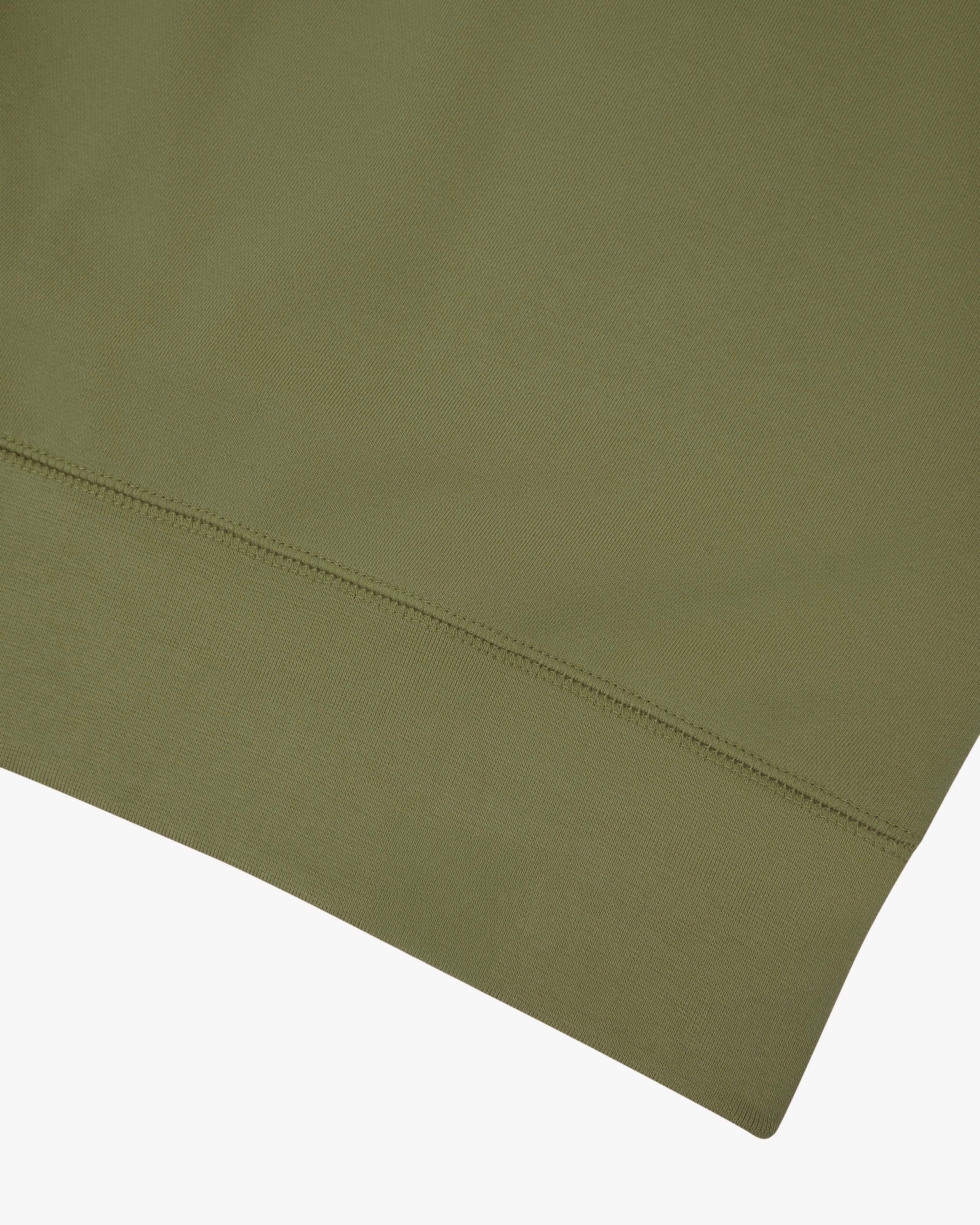 Close-up of an Uskees herb green sweatshirt showing the hem detail