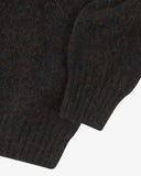 Close-up of a dark brown knitted sweater sleeve on a white background