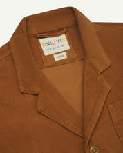 Front close-up view of tan corduroy blazer from Uskees, showing collar and brand label at neck.