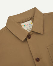 Front close-view of khaki buttoned shacket from Uskees. Showing neck label and corozo buttons.