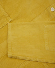 Close up shot of  sleeve/front of acid yellow coloured, buttoned corduroy overshirt from Uskees. 