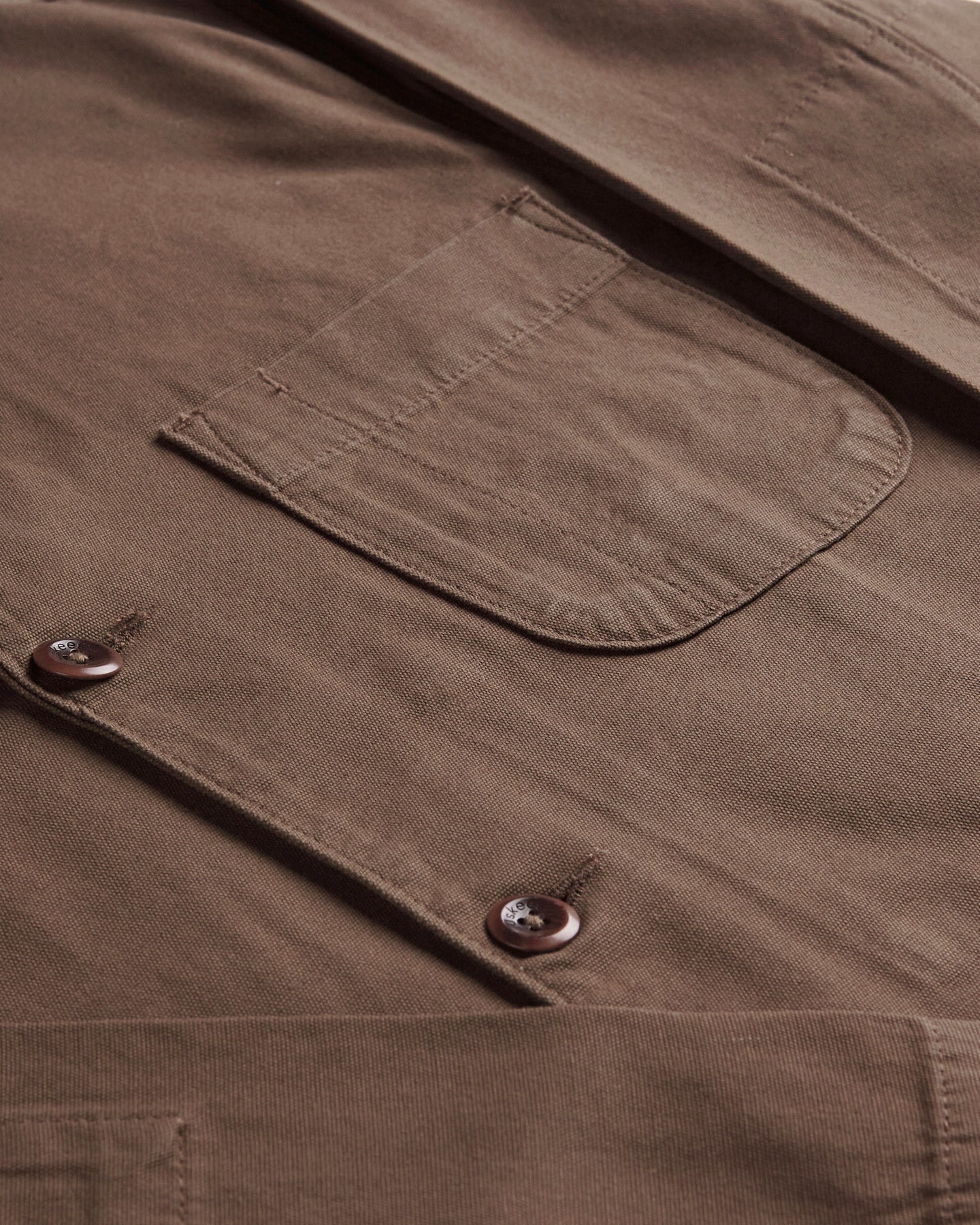 Mid-right view of #3006 Uskees blazer in 'chocolate' coloured cotton with focus on breast pocket and corozo buttons.