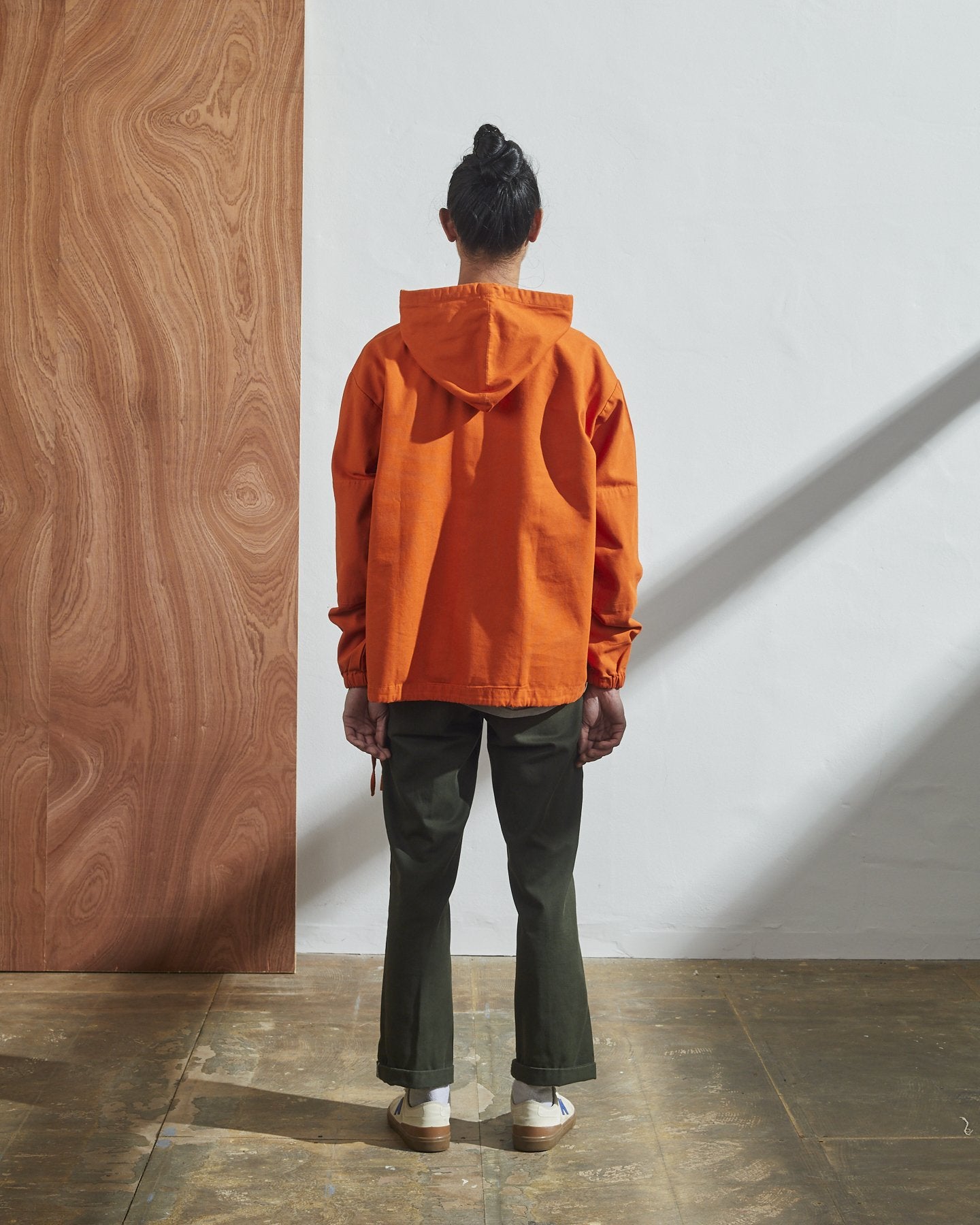 Full-length rear view of model wearing Uskees smock in gold-orange organic cotton.