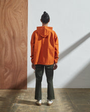 Full-length rear view of model wearing Uskees smock in gold-orange organic cotton.
