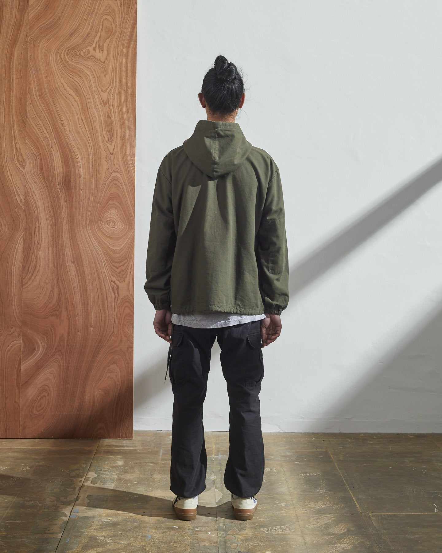 Full-length rear view of model wearing Uskees Smock in olive green organic cotton.