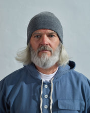 Model wearing Uskees 4004 grey lambswool hat, paired with blue Uskees smock.