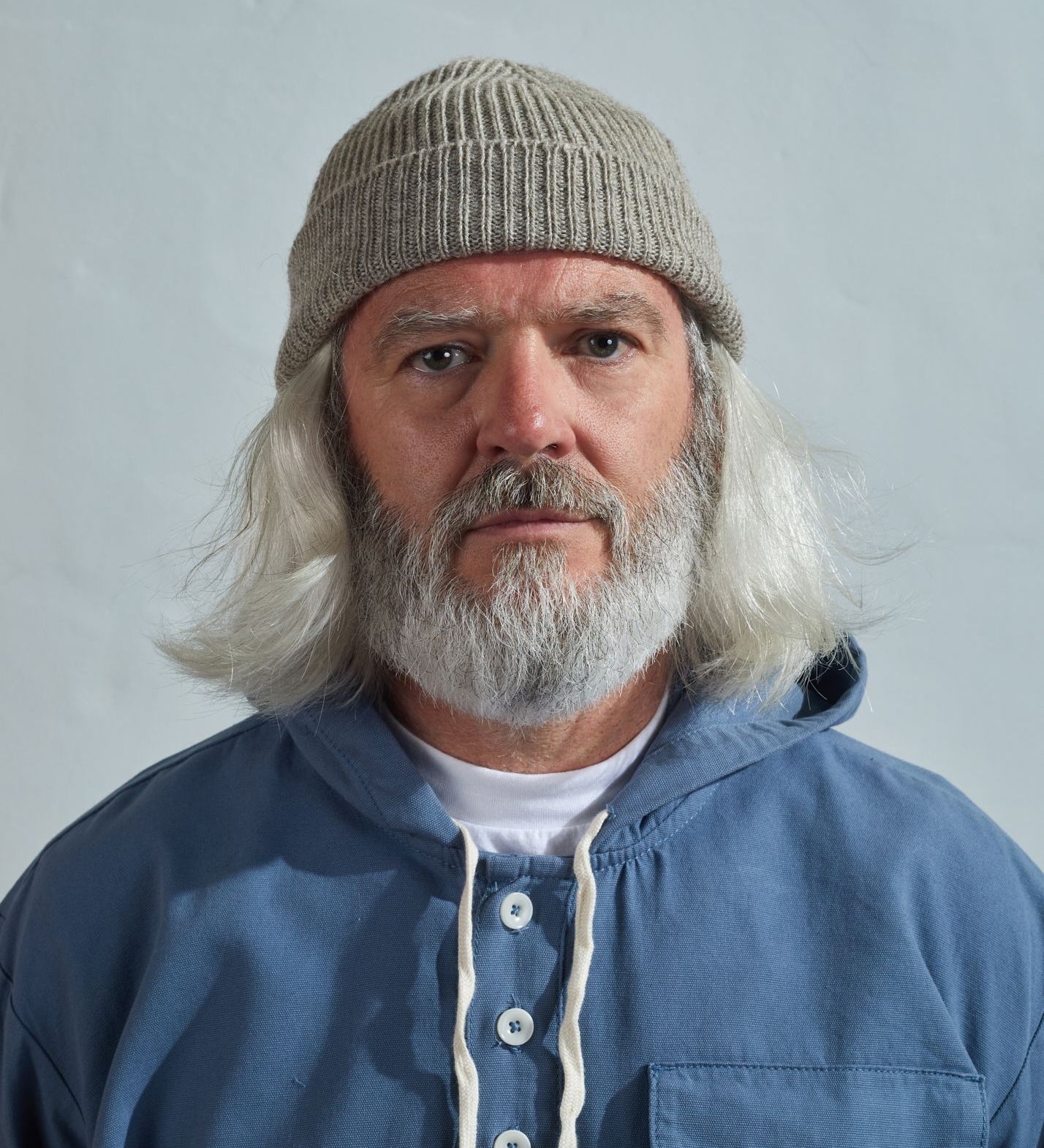 Model wearing Uskees 4005 'light oat' off-white coloured wool hat, paired with blue Uskees smock.