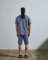 Full-length back view of model wearing teal, relaxed cut organic cotton #7006 jersey T-shirt by Uskees paired with matching #7007 shorts.