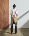 Back view model shot of khaki #9003 Japanese style apron by Uskees. Showing cross-back straps.